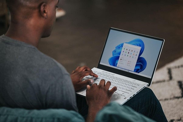 man in gray long sleeve shirt using Windows 11 computer