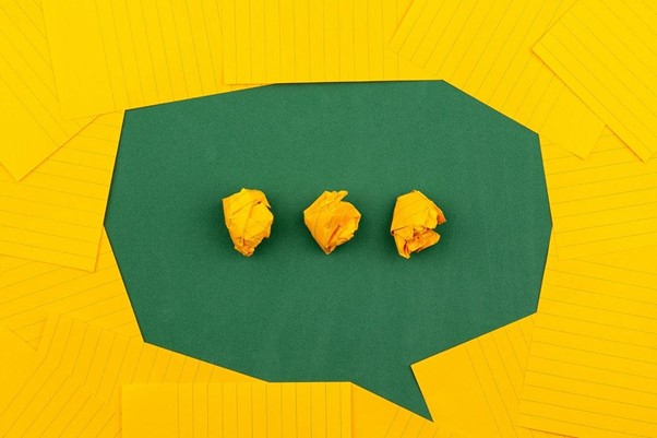 three crumpled yellow papers on green surface surrounded by yellow lined papers